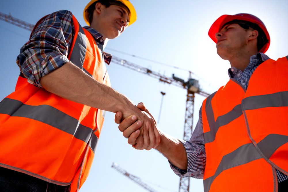 two happy construction professionals shaking hands; positive work culture